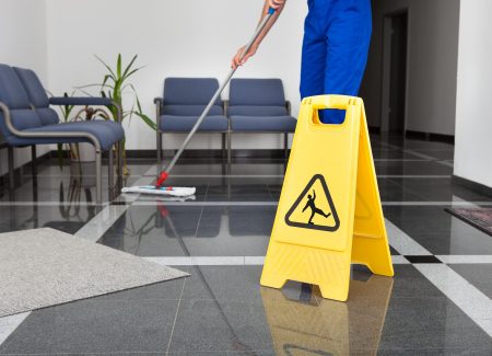 A wet floor sign and someone mopping a floor. 