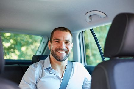 Smiling passenger sitting in the back of a car