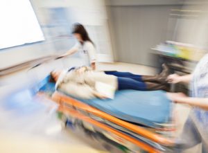 A blurred image of a doctor wheeling a patient through the hallways of a hospital on a gurney