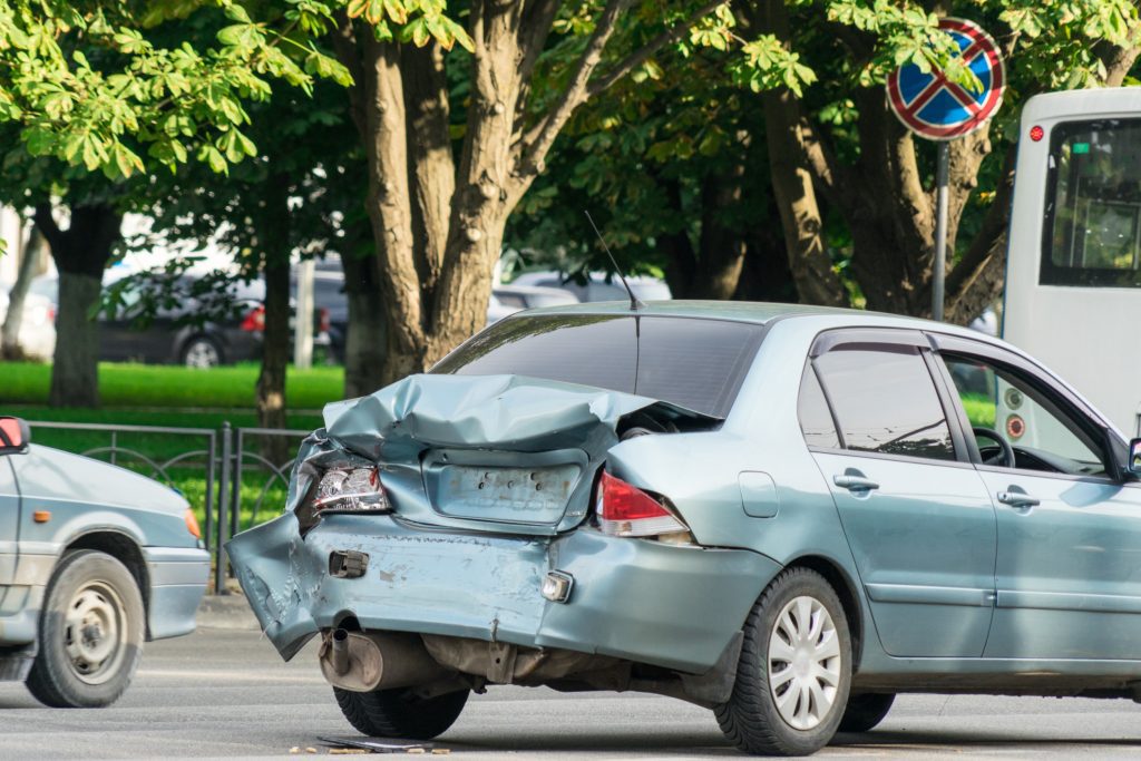 The back of a blue car smashed on the road. 