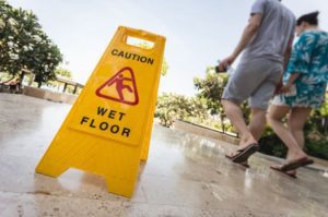 Two men walk past a wet floor sign