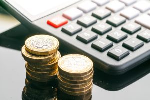 Two stacks of coins next to a calculator.