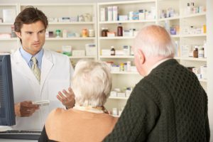 A pharmacist gives medication advice to an elderly couple.