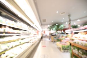 A blurred image of a supermarket showing fruits and vegetables.