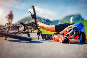 A cyclist lying on the floor after falling of their bike in an accident.