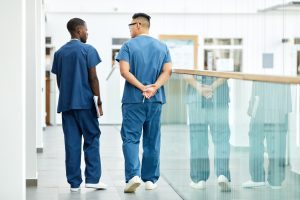 Two male medical professionals walking in a hospital corridor together.