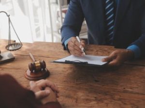 A data breach solicitor holding a pen and form while sat in front of a client