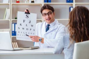 An optician with a patient holds a letter chart