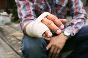 A close-up of an injured hand covered in a bandage.
