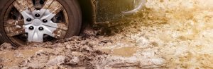 A close up of a care tires driving through mud