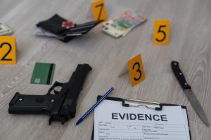 A murder scene with evidence marked including a gun, a knife and a pile of cash notes.