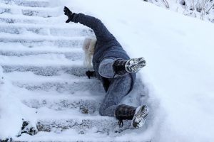 A person slips down snow covered stairs. 