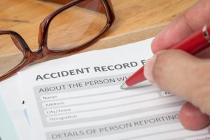 A person fills in an accident record form. 