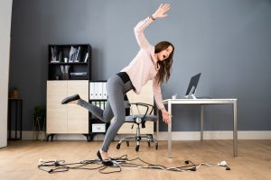 A woman sustaining workplace injuries after tripping over trailing wires in an office