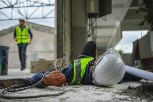 An electrical worker lays on the ground. 