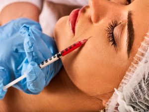 A professional applies a dermal filler to a womans face. 