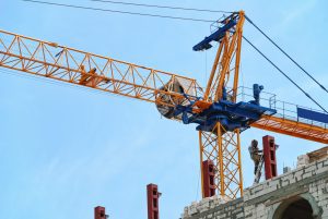 A crane on top of a building with a person working. 