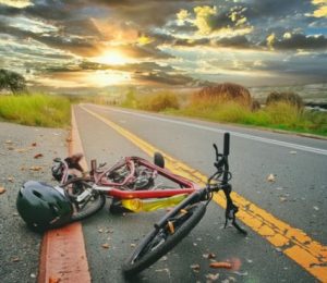 A crashed bicycle and a helmet lying on the side of a road