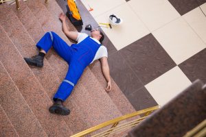 An injured worker lying at the bottom of a flight of stairs.
