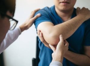 Physical therapist examining a patient's injured arm and elbow