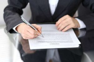 A personal injury solicitor sat at a glass table and reviewing a contract agreement form