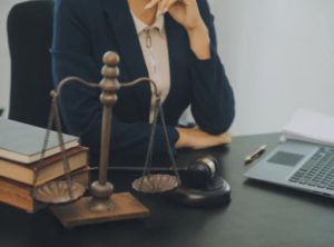 A road traffic accident solicitor sat at a desk with a laptop, books, a gavel and scales of justice nearby.