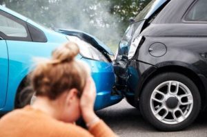 Female motorist with head in their hands near two damaged cars involved in a road traffic accident