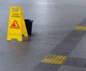 Wet floor sign and a bucket on the ground in a public area