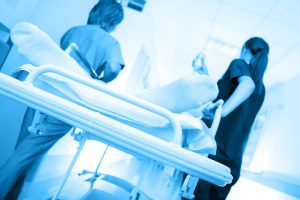 Medical staff take a patient on a bed through a hospital. 