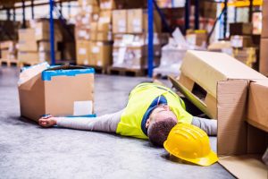 A worker lays on the floor surrounded by boxes. 