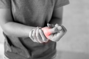 A balck and white image of someone holding their wrist in pain.