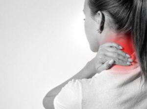 Woman holding back of injured neck in discomfort