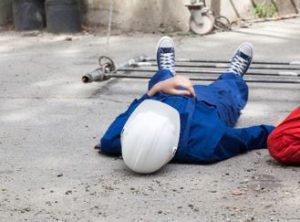 An injured construction worker lying on his back after an accident