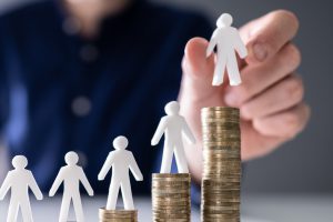 Plastic men held over stacks of coins showing how compensation is calculated. 