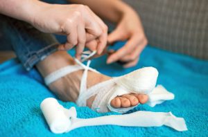 A woman bandages a foot with a minor injury.