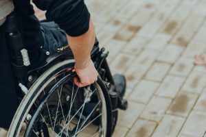 A paralysed person in a wheelchair holding the wheel.