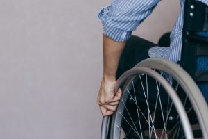 A person with paralysis injuries sat in a wheelchair holding the wheel. 