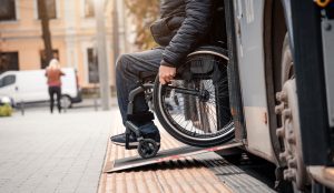 A man in a wheelchair exiting a bus using a ramp.