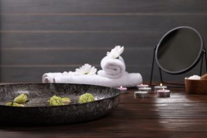 Bowl of water, flowers and burning candles on wooden table,