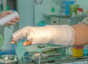 A burned arm is wrapped in white gauze in a clinical-looking room.