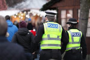 Police officers stand behind a blurred crowd.