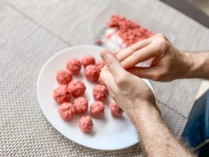 A person handles raw meat with their bare hands. 