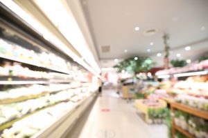 A blurred image shows supermarket shelves of food. 