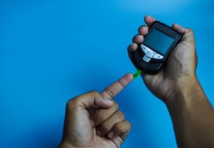 PERSON CHECKING THEIR BLOOD SUGAR WITH A FINGER TIP READER