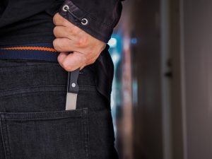 A man placing a knife into his back pocket