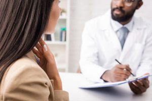 Doctor sits with patient in bright room as they diagnose lung cancer.