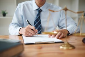 Lawyer reviews lung cancer misdiagnosis notes at desk featuring scales of justice.