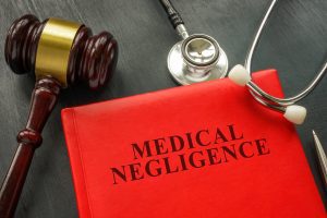 A red folder that reads 'medical negligence' with a wooden gavel and stethoscope 