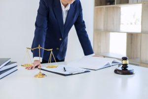 A solicitor stands over a desk with paper work, a gavel and scales of justice