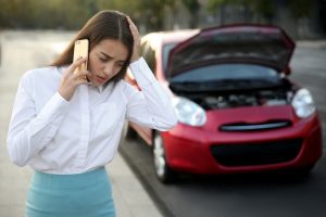 Woman on phone next to car.